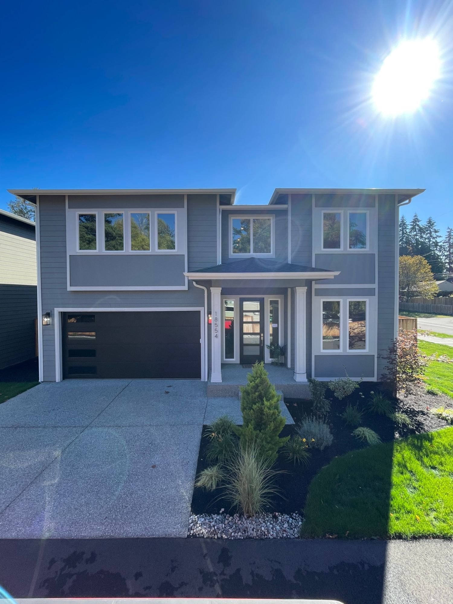 Front of the new Stone Ave home: grey lap siding, white trim, covered entry and black garage door